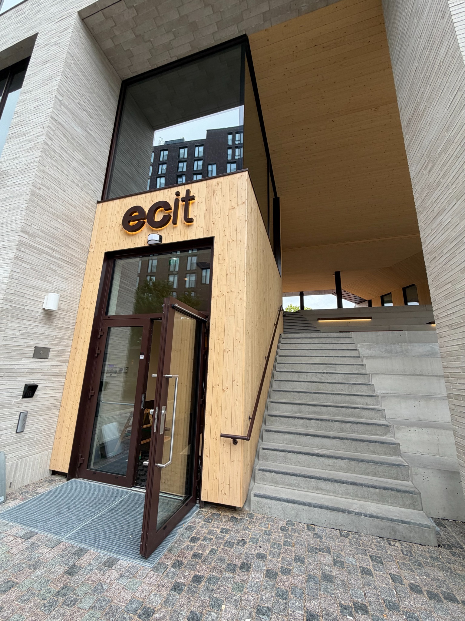 Inngangsparti med trekledning og trapp opp til atriet.